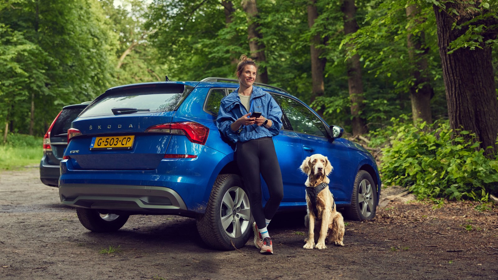 Vrouw en hond zitten in de open kofferbak 