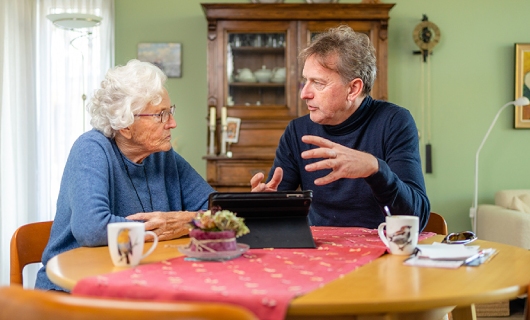 Gerben en zijn schoonmoeder zitten aan tafel achter de tablet
